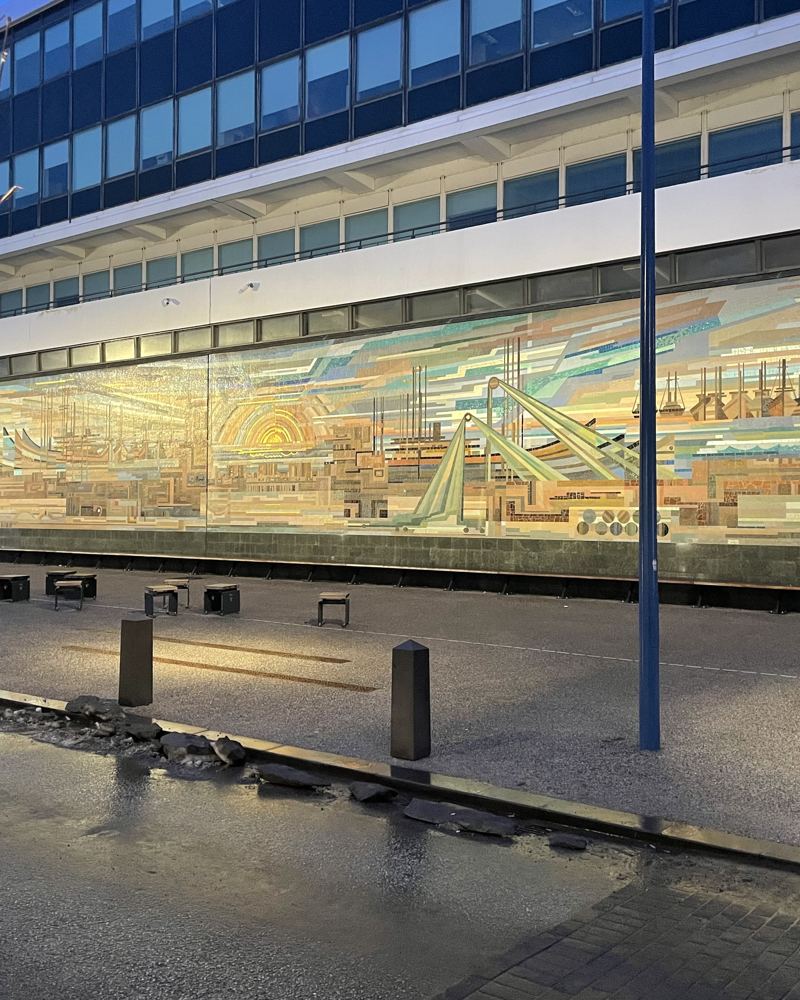 A long mosaic mural along a Reykjavík street at dusk